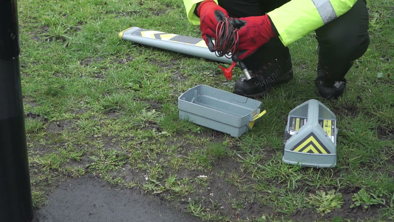 An operative kneeling at a street lighting column connecting a Genny lead